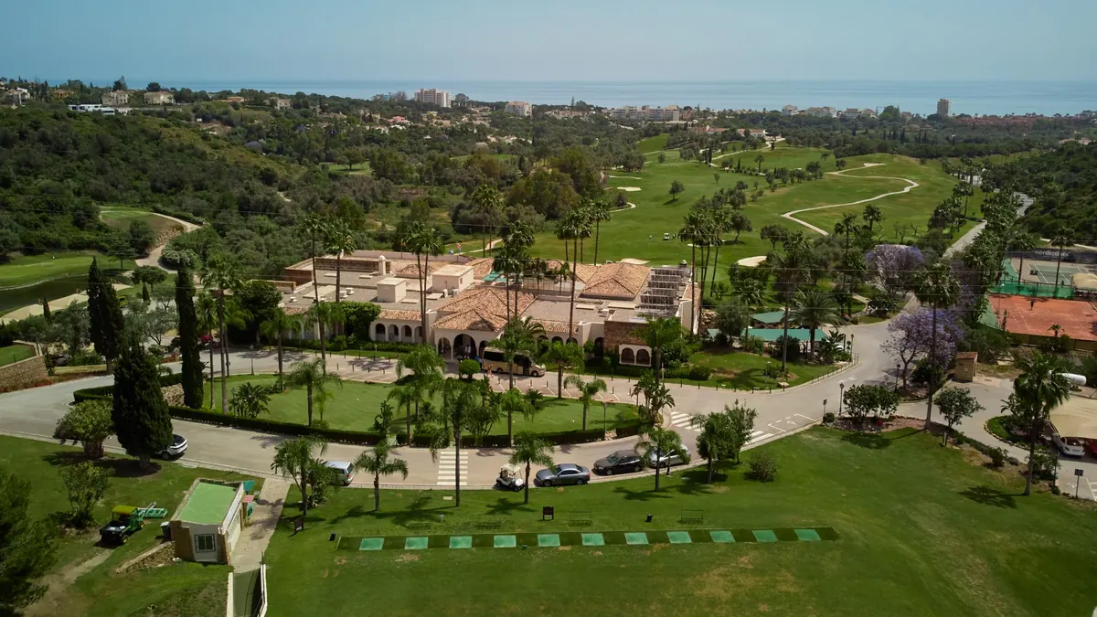 Aerial photograph of Marbella Golf’s clubhouse, practice area and fairways with the Mediterranean in the distance